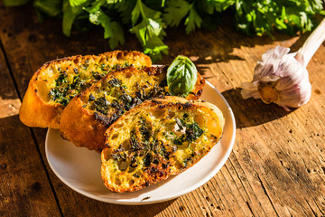Traditional French toasts with butter, parsley, garlic and basil on an old rustic wooden table