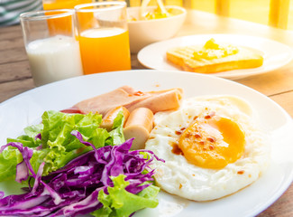 American breakfast with sunny side up eggs,ham, bacon, coffee and juice, and salad on the table
