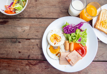 American breakfast with sunny side up eggs,ham, bacon, coffee and juice, and salad on the table