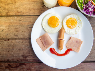 Top of Smile, happy breakfast for kids, egg,ham,sausage,salad,milk and orange juice on plate