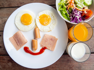 Top of Smile, happy breakfast for kids, egg,ham,sausage,salad,milk and orange juice on plate