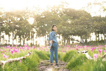 Young woman enjoying walking of pink flower field in Thailand