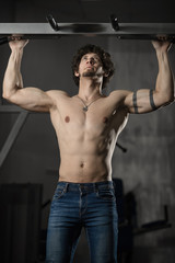 Fototapeta na wymiar Man in gym making Pull-up. Bodybuilder training in gym