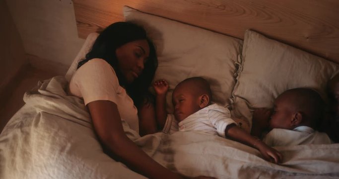 Young loving couple sleeping in bed with little sons