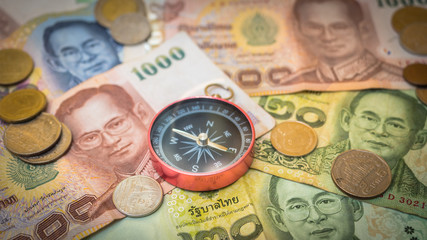 Compass on pile of thai money