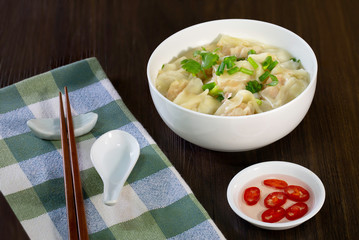 Shrimp wonton in hot soup in white bowl on wooden table Asia food