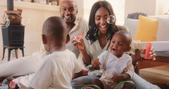 Happy parents playing with children and blowing bubbles at home