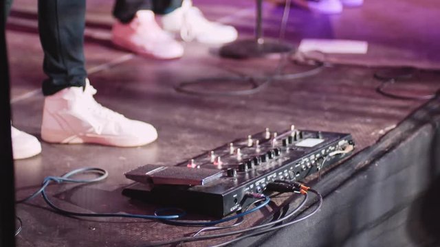 Guitar pedal and guitarist foot playing at a concert. 