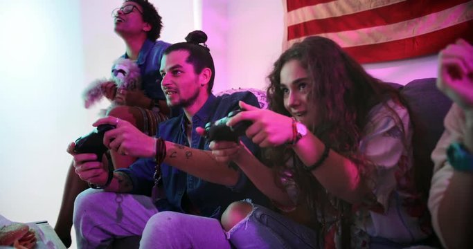 Young hipster friends relaxing at home and playing video games