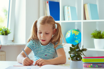 Portrait of schoolgirl at classroom writing at the table