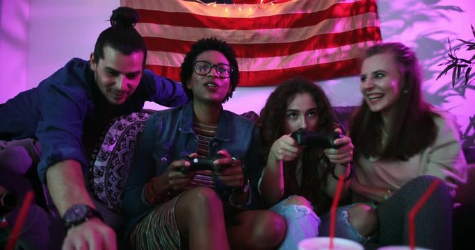 Young multi-ethnic friends playing video games and eating fast food