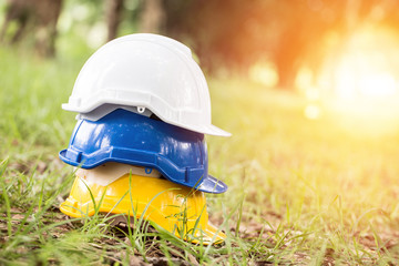 Stack of Engineer safety helmet yellow blue and white on green grass