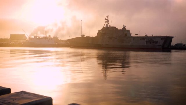 Slow motion view of a US Army battleship anchored in a harbor at sunset