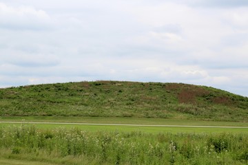 Fototapeta premium The green grass hill landscape with overcast skies. 