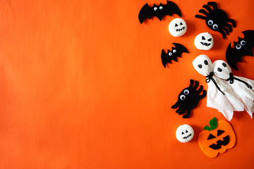 Top view of Halloween crafts, orange pumpkin, ghost and spide on orange background with copy space...