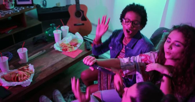 Young multi-ethnic hipster friends partying and singing together at home