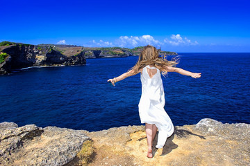 girl in white dress on cliff near the ocean