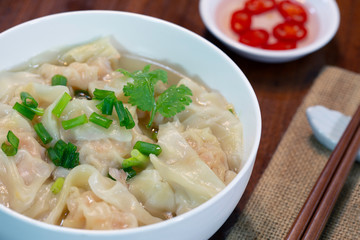 Shrimp wonton in hot soup in white bowl on wooden table Asia food