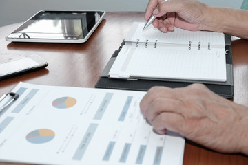 financial inspector analyze sales document at office. man writing note on notebook