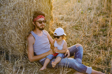 Naklejka na ściany i meble father and son in t-shirts sitting next to a haystack