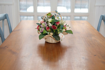 Fototapeta premium artificial rose bouquet on wood table in cozy dining room interior