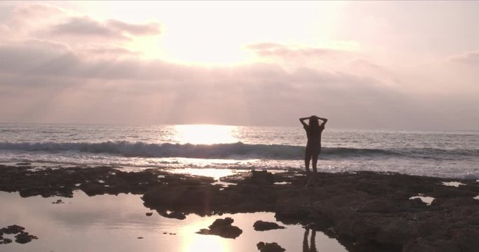 Aerial view of woman relaxing at beach with arms outstretched