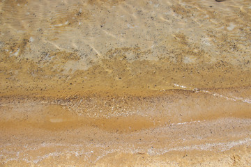 Fototapeta na wymiar Background Brown sand through the clear waters of the dead sea