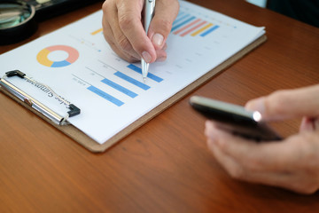 man working with smart phone at office. businessman analyzing chart document at workplace.