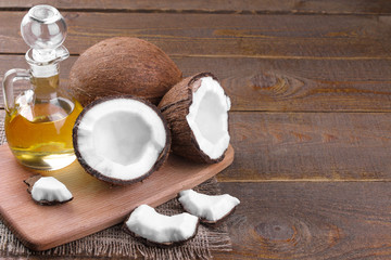 Coconut with slices of coconut and coconut oil on a brown wooden background