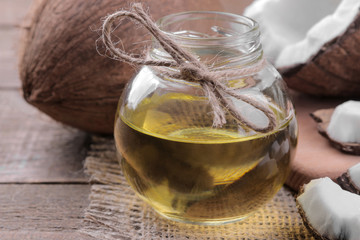 Coconut with slices of coconut and coconut oil on a brown wooden background