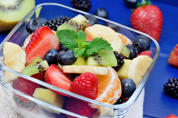 Fresh fruit salad in a bowl on blue wooden table