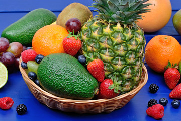 Mix of healthy fresh fruits in a basket on wooden table