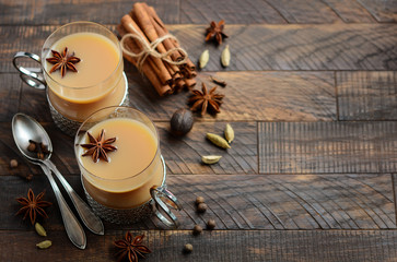 Indian masala chai tea. Spiced tea with milk a vintage cups on the rustic wooden table.