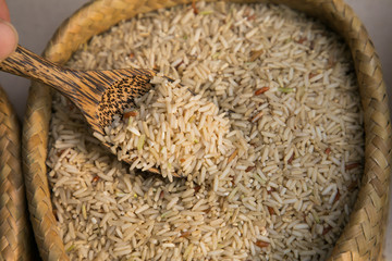 Organic brow jasmine rice and wood spoon in weave stock. Food background