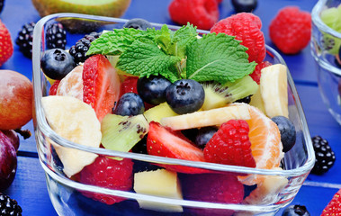Colorful fruit salad in a transparent bowl on table