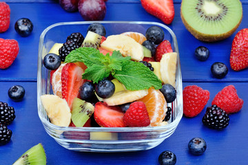 Fruit salad in a transparent bowl on wooden background