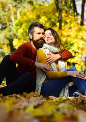 Couple in love with scarves sits on leaves in park