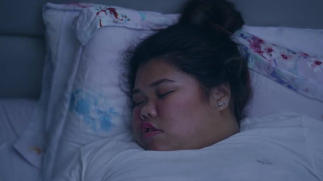 Overweight young woman sleeping and snoring in her bed at night. Shot in 4k resolution
