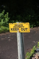 A bright yellow and black sign that states Private Property Keep Out