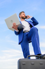 Man well groomed businessman holds laptop blue sky background. Confident entrepreneur. Guy formal suit modern technology manager entrepreneur put foot on briefcase. Top qualities excellent manager