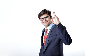 Young Indian businessman making an OK gesture over isolated white background