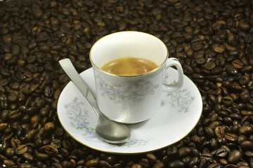 Portrait of a white cup of coffee on many coffee beans with white background. Concept: Relax, flavor, breakfast, drink