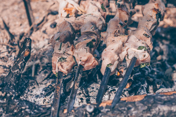Pork meat is fried on an open fire in a hike