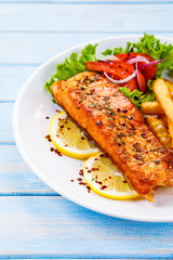 Fried salmon, French fries and vegetables 