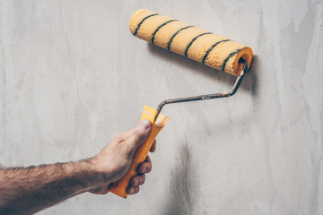 The worker moisturizes the old wallpaper for dismantling with a paint roller