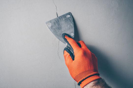 Worker repairs a crack in the wall from shrinkage of the building or poor-quality work