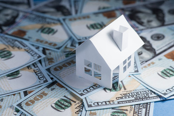 White paper house on one hundred dollar bills close up. Real estate prices concept