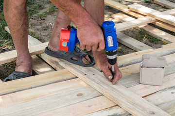 Drill wood workshop. Woodwork and people concept - carpenter with battery power drill drilling wood...