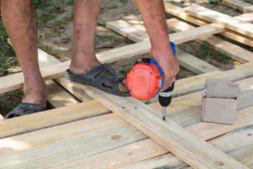 Drill wood workshop. Woodwork and people concept - carpenter with battery power drill drilling wood plank at workshop, Formwork for the fence