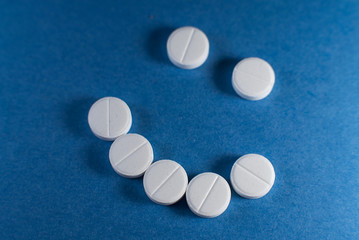 Happy smile made from white pills on blue background